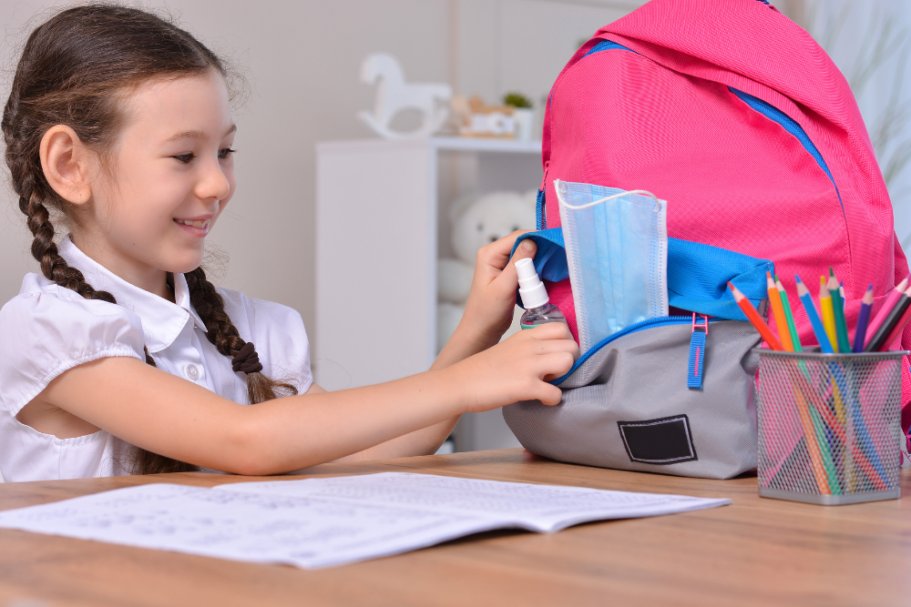 Bambina mette il gel igienizzante nello zaino per prepararsi ad andare a scuola