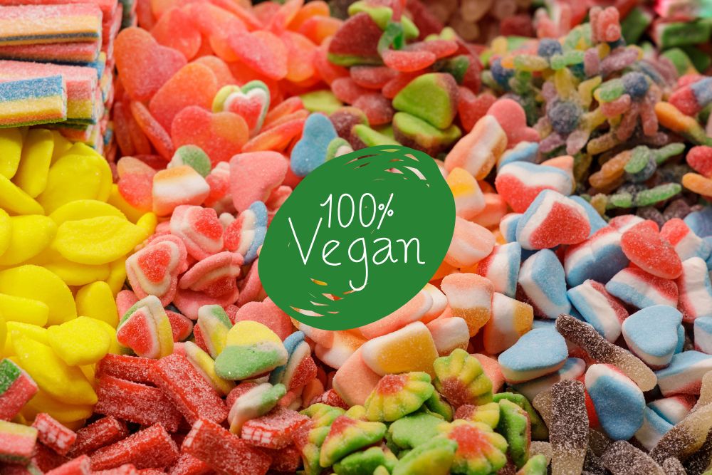 Assortimento colorato di caramelle gommose 100% vegane di varie forme e gusti, impilate insieme.