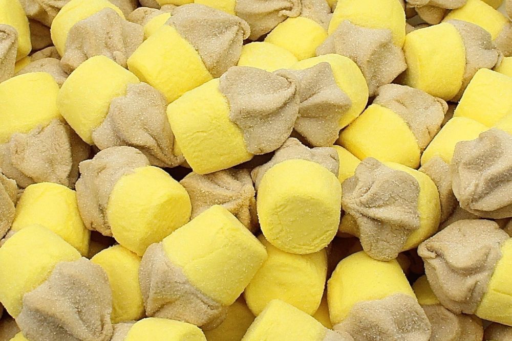 Marshmallow a forma di piccoli cupcake colore giallo e beige ripieni di cioccolato disposti alla rinfusa