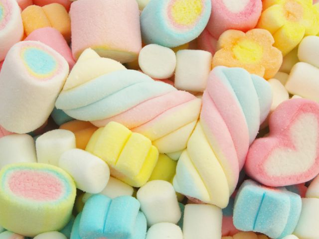 Assortimento di una varietà di marshmallow colorati con forme a spirale, cuore e fiore in tonalità pastello.