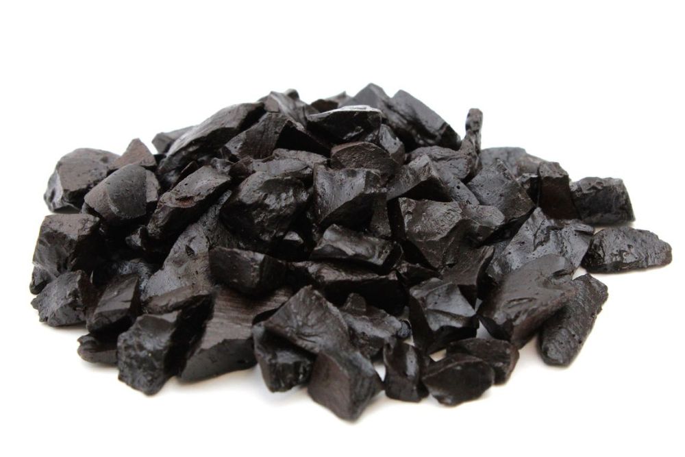 Pezzetti irregolari di Liquirizia Pura di Shiraz Kordofan frantumata disposte a mucchietto su sfondo bianco
