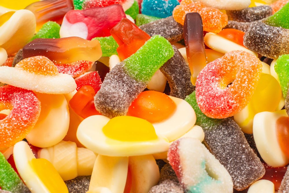 Varietà di caramelle gommose colorate di diverse consistenze con forme di uova fritte, bottiglie e anelli zuccherati.