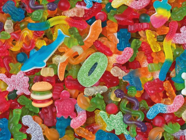 Una varietà colorata di caramelle gommose a forma di vermi, orsetti, hamburger e animali in un mix vivace.
