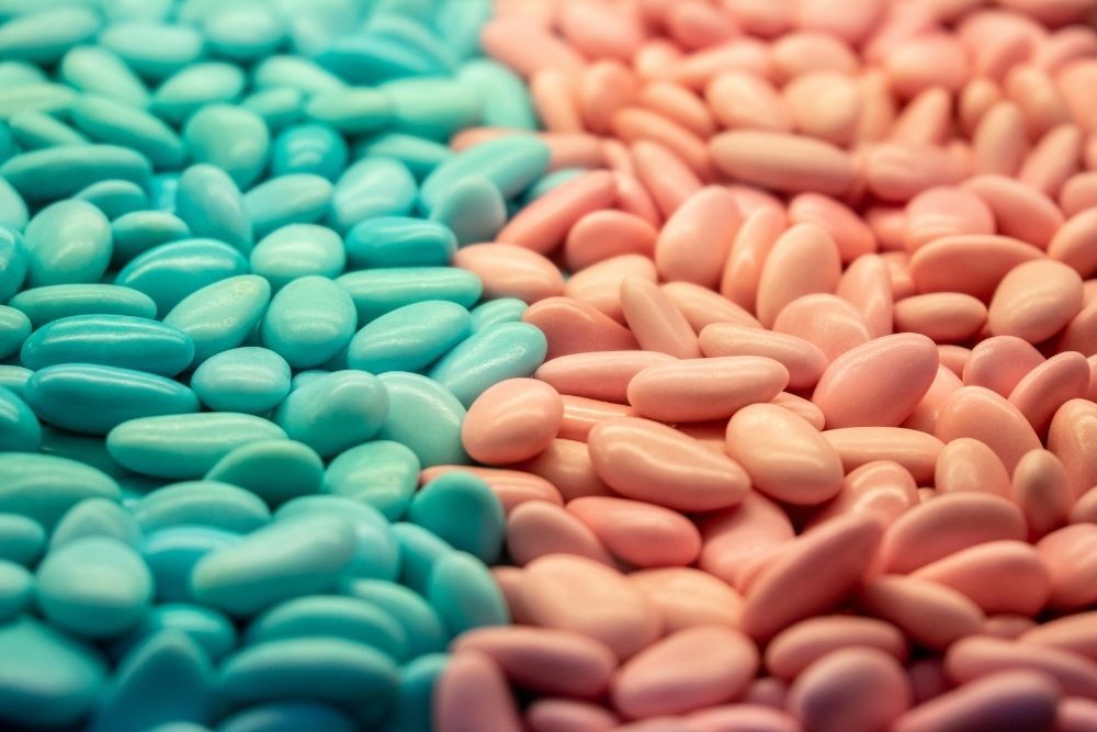Primo piano di numerosi confetti azzurri e rosa disposti fianco a fianco divisi per colore