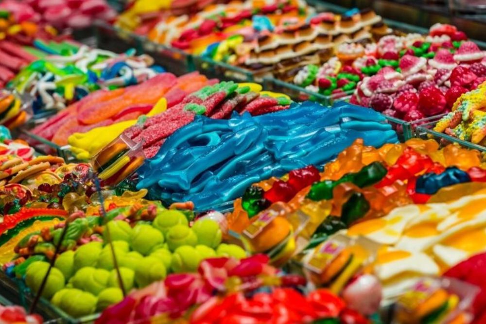 Banco colorato con una varietà di caramelle gommose e zuccherate disposte in file ordinate