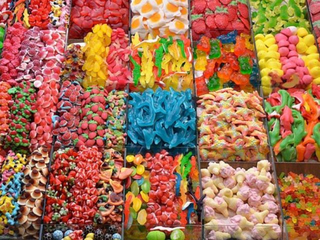 Varietà colorate di caramelle gommose disposte ordinatamente in vassoi rettangolari