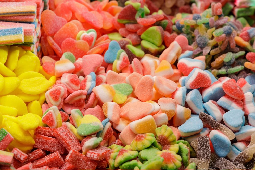 Varietà colorata di caramelle gommose a forma di cuore, frutta e altre forme dolci assortite in esposizione