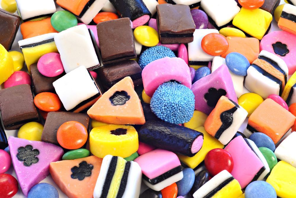 Primo piano di liquirizia allsorts o liquirizia inglese formata da una varietà di caramelle assortite e colorate con forme quadrate, triangolari e rotonde.