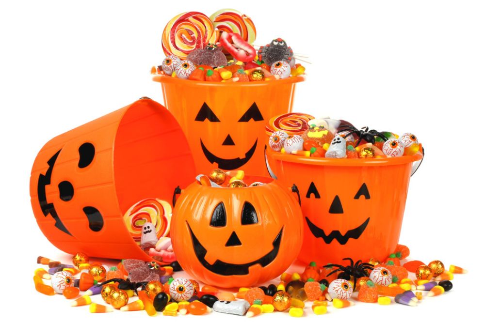 Tre secchi arancioni a forma di zucca di Halloween pieni di caramelle assortite e dolcetti colorati.