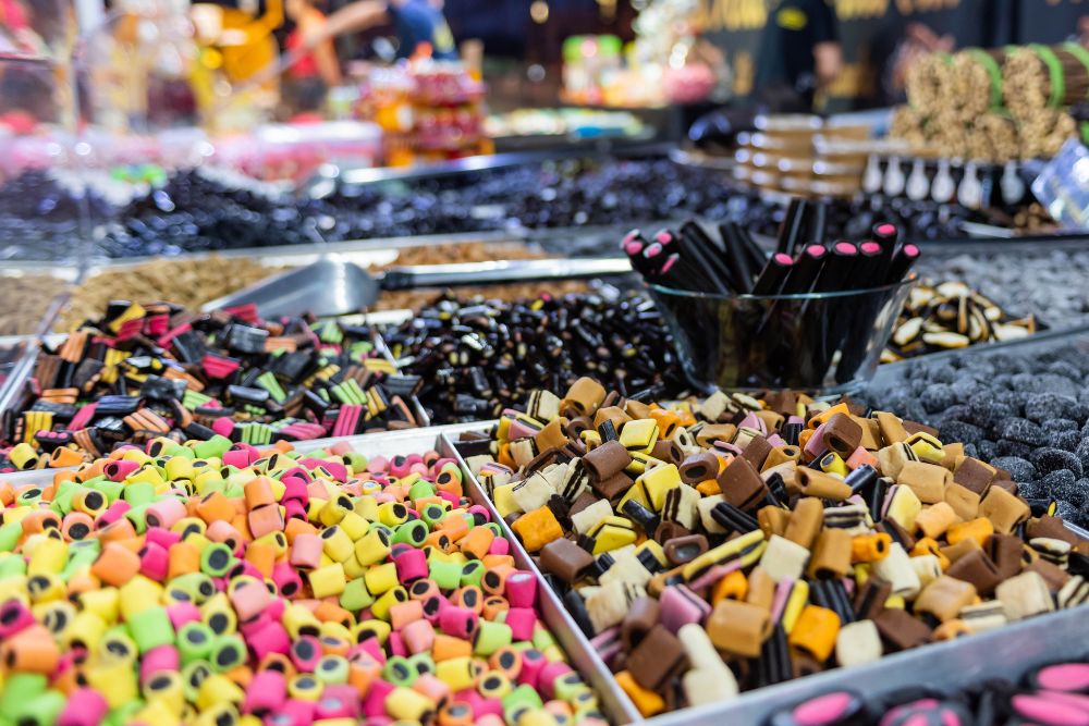 Vassoi pieni di diverse tipologie di caramelle alla liquirizia colorate e invitanti in un mercato.